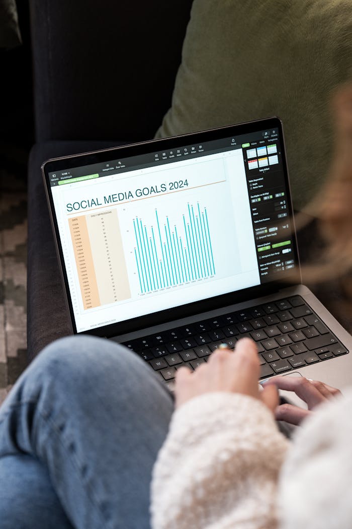 about-01 Woman reviewing 2024 social media goals chart on laptop indoors.
